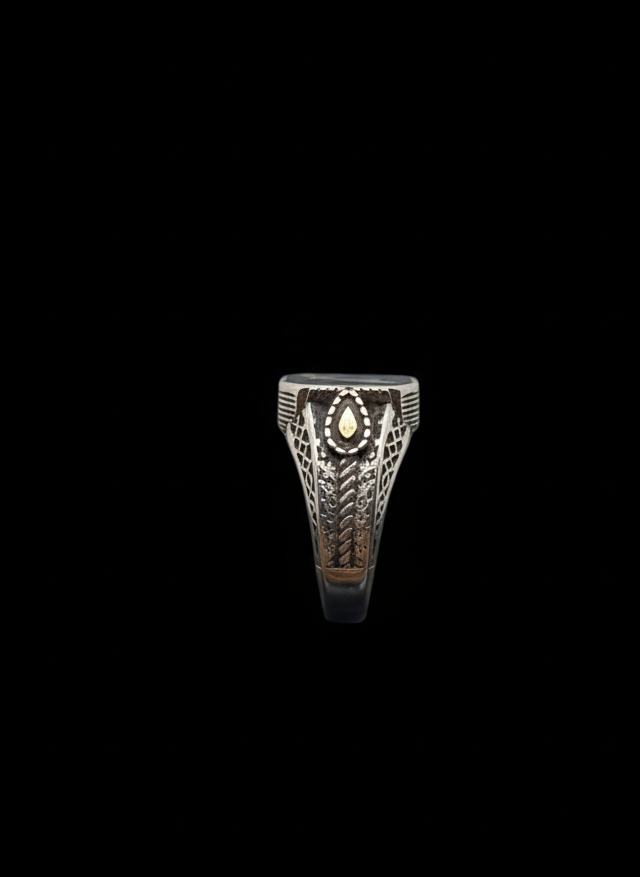 Silver ring with intricate design on a black background