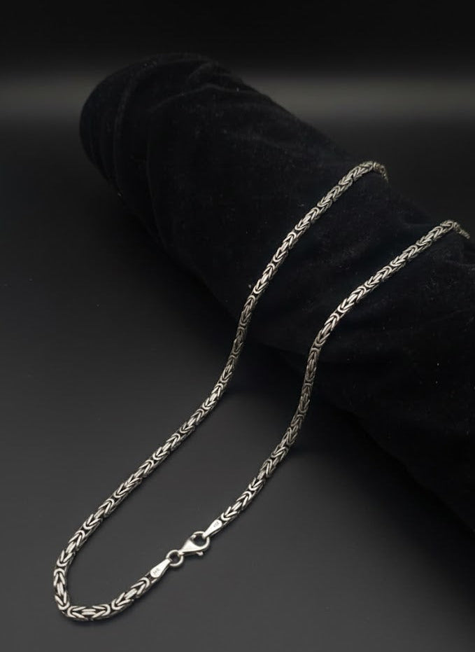 Silver chain necklace on a black velvet surface